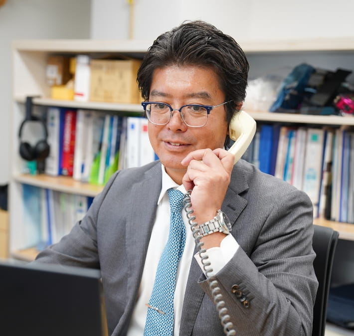 スーツ姿の男性が電話で会話をしながら、営業している。