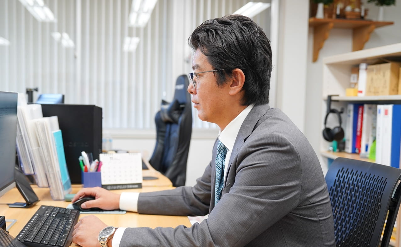 デスクでパソコンに向かい、集中して作業を行っている