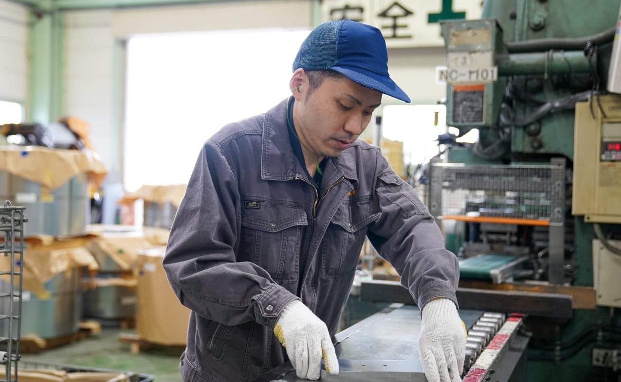 手袋を着用し、真剣な表情で作業台の上で部品の検査または加工を行っている。