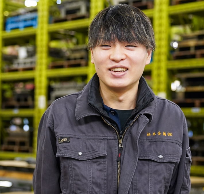 作業服を着た男性が工場内で笑顔で話をしている。